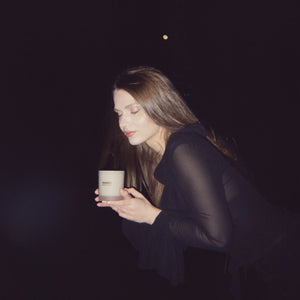 Woman holding a Vanam candle against a dark background