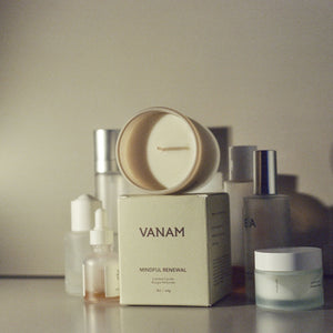 Vanam beeswax candle surrounded by modern skincare essentials